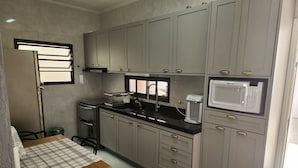 Une cuisine de taille réduite avec des meubles gris, un four à micro-ondes, une cuisinière et un évier.