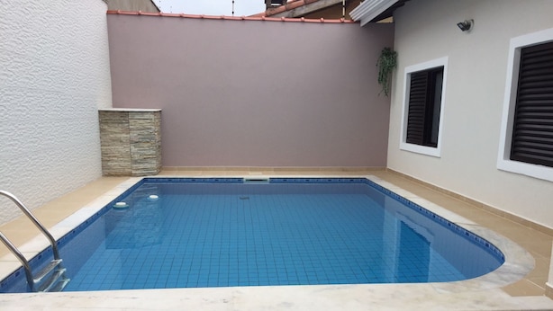 Une piscine rectangulaire dont le fond est recouvert de carreaux bleus et dont le bord est blanc.