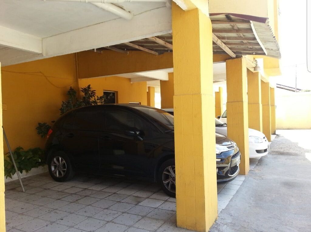 A parking garage with yellow pillars and a black car parked under a covered area.