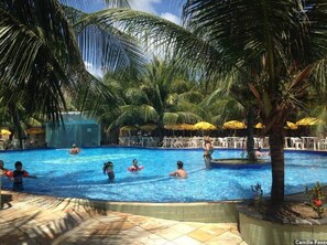 A swimming pool surrounded by palm trees and umbrellas.