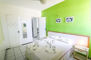 A hotel room with a bed, a bedside table, a mirror, and a green accent wall.