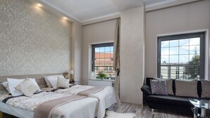 Een hotelkamer met een groot bed, een bank, een klein tafeltje en twee ramen.