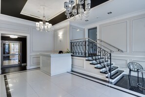 A spacious lobby with a grand staircase, a reception desk, and a chandelier. - Elite Apartments Tartaczna DeLuxe (Gdansk)
