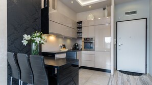 Een moderne keuken met een marmeren aanrecht, zwarte stoelen en een vaas met bloemen.