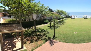 A well-maintained lawn with a wooden pergola and a gazebo, overlooking a beach. - Flamboyant Hotel (Barra Velha)