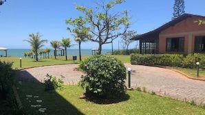 A paved pathway leading to a building with a view of the sea. - Flamboyant Hotel (Barra Velha)