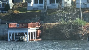 A waterfront house with a dock, a covered area, and a staircase leading up to the main house. - Winnipesaukee - Lakefront house includes slip, deck, kayaks & sleeps up to 11 (Alton)
