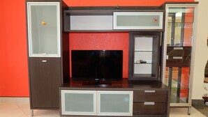 A modern entertainment unit with a flat-screen TV, built-in cabinets, and a glass display cabinet.