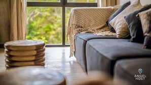 Un salón acogedor con un sofá, un plaid tejido y una pila de posavasos de madera.