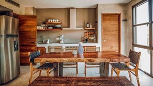 Una cocina moderna con una mesa de comedor de madera, sillas y un refrigerador de acero inoxidable.