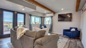 A living room with a grey sofa, a blue armchair, and a flat-screen TV on the wall. - 4 BD Entire House Located Close to Downtown and Little Italy! (San Diego)