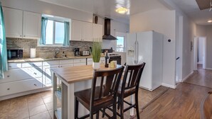 A modern kitchen with white cabinets, a wooden dining table, and two chairs. - 4 BD Entire House Located Close to Downtown and Little Italy! (San Diego)