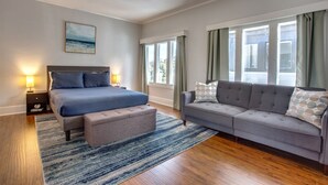 A bedroom with a bed, a sofa, a ceiling fan, and a window with curtains. - 4 BD Entire House Located Close to Downtown and Little Italy! (San Diego)