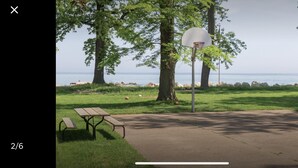 Um parque com uma cesta de basquete, mesa de piquenique e vista para o mar.