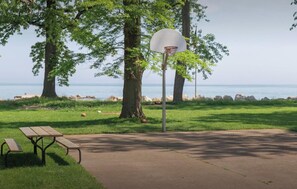 Una cancha de baloncesto con aro, una mesa de picnic y vista al mar.