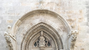 Una entrada de pedra amb arc apuntat, emmarcada per columnes i detalls ornamentals.