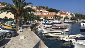 Un port esportiu amb vaixells amarrats, un passeig pavimentat i edificis amb teulades vermelles al fons.