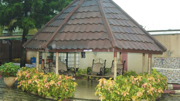 A small pavilion with a tiled roof, surrounded by potted plants, and featuring outdoor seating. - Chisam Suites Annex (Port Harcourt)