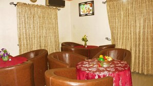 A dining area with brown leather chairs, a table with a red tablecloth, and a fruit bowl. - Chisam Suites Annex (Port Harcourt)