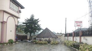 A hotel with a covered outdoor seating area, a paved courtyard, and a sign indicating the hotel's name. - Chisam Suites Annex (Port Harcourt)