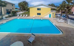 Relax by the pool surrounded by lush vegetation and lounge chairs.
