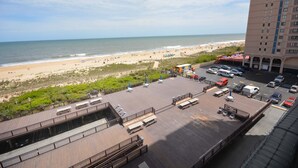 Un grand hôtel situé dans un immeuble de grande hauteur, donnant sur une plage, avec un espace de stationnement et une vue sur l’océan.