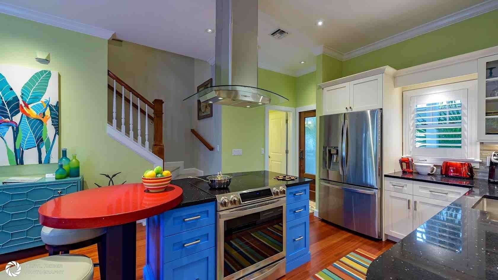 Una cocina moderna con una isla central, electrodomésticos de acero inoxidable y una paleta de colores vibrante.
