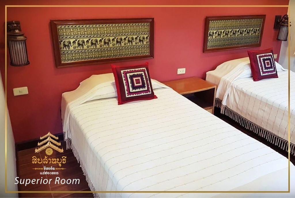A Superior Room with two beds, each with a patterned pillow, a nightstand, and wall-mounted decorative panels.