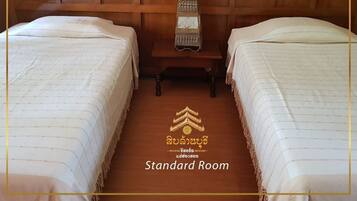 A standard room with two beds, a wooden headboard, and a small table with a woven basket.