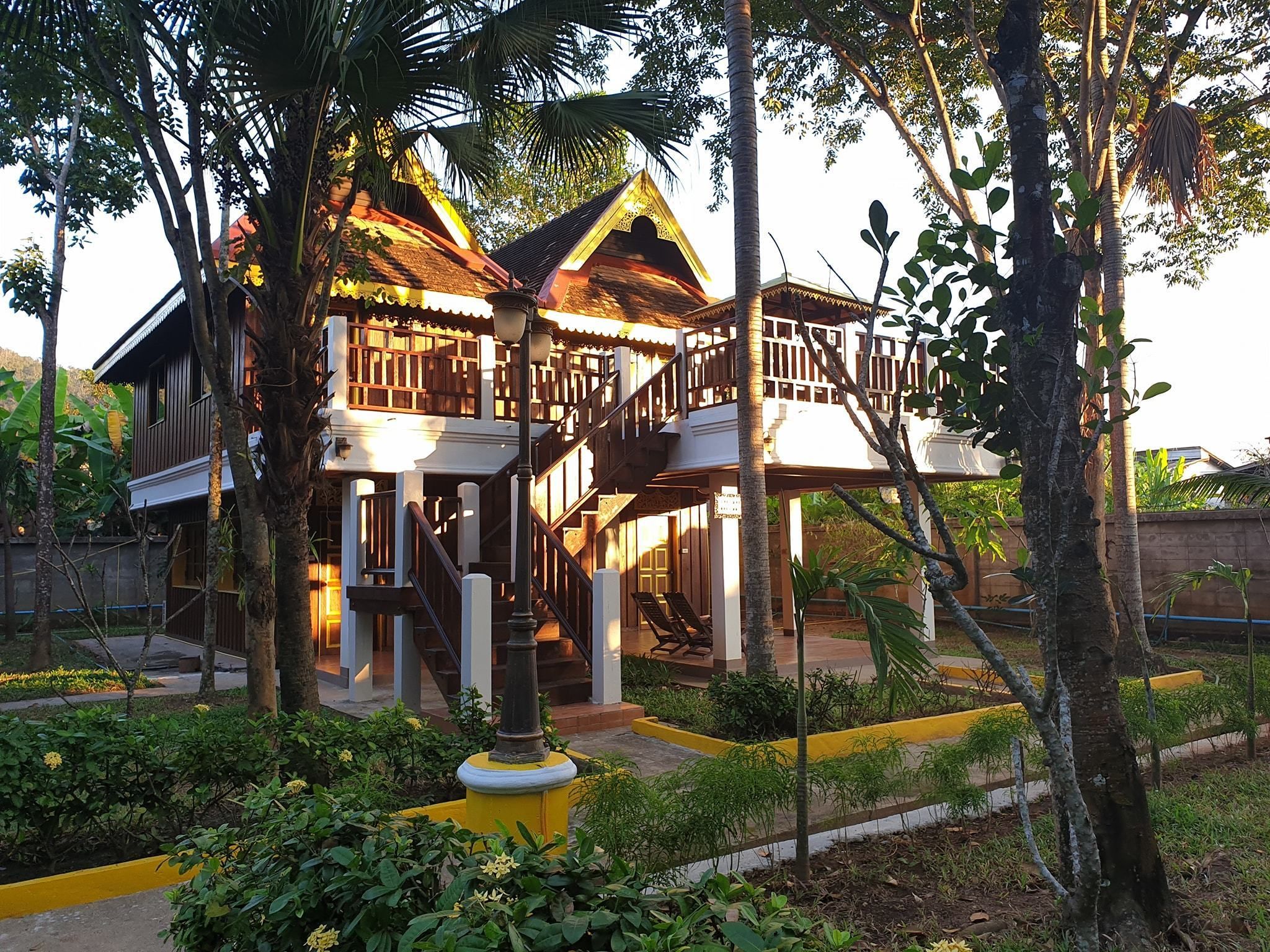 A traditional wooden house with a balcony and a staircase leading to the upper floor.
