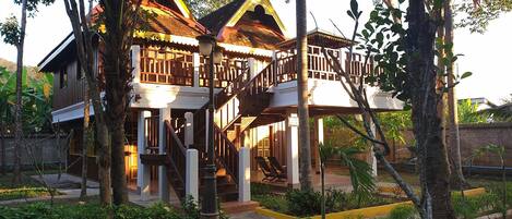 A traditional wooden house with a balcony and a staircase leading to the upper floor.