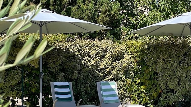 Una piscina con sillones de descanso y sombrillas.