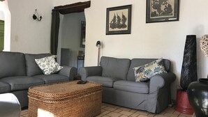 Una sala de estar con dos sofás grises, una mesa de centro tejida y un jarrón negro grande.