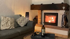 Una sala de estar acogedora con chimenea, un sofá y una mesa de centro con una botella y vasos.