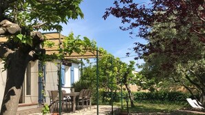 Un patio con mobiliario exterior, una mesa pequeña y plantas en macetas.