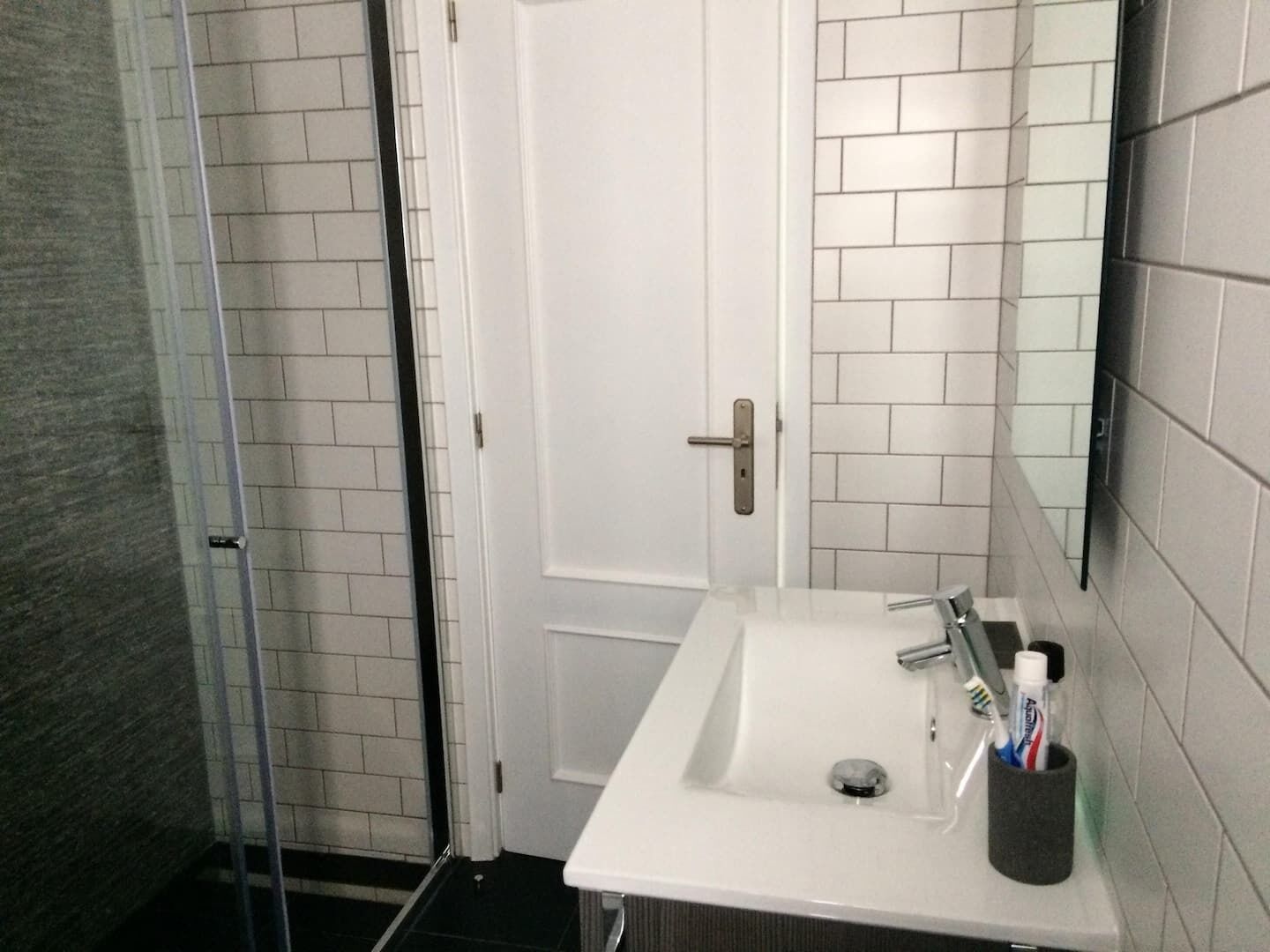 A bathroom with a white sink, a mirror, and a door.