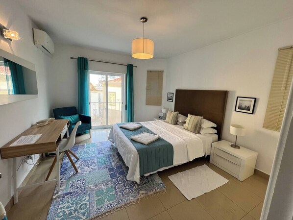 A hotel room with a bed, a desk, a chair, a balcony, and a view of the outside. - Chic apartment in top location fast WiFi Smart TV (Lagos)