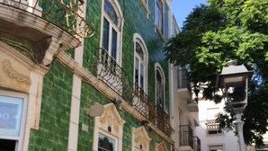 Un bâtiment historique à la façade verte et blanche, doté de balcons richement décorés et situé sur une rue pavée.