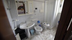 Un baño con lavamanos, bidé, inodoro y ducha.