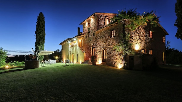 Un edificio in pietra con un'ampia area patio, posti a sedere all'aperto e un ingresso ben illuminato.