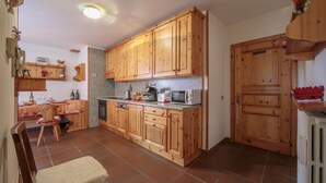 A kitchen with wooden cabinets, a microwave, and a sink. - Martina Ski in - Ski out 50m, Livigno, Italy (Livigno)