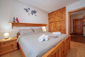 Een keurig opgeruimde slaapkamer met een bed, nachtkastjes, een houten garderobe en een wereldkaart aan de muur.