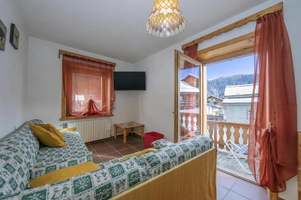 Wohnbereich mit Wandfernseher und Zugang zum Balkon