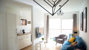 Un salon moderne avec un canapé bleu, une petite table et un téléviseur fixé au mur.