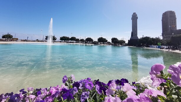 Un ciel d’un bleu éclatant, une fontaine et un monument sur une place publique.