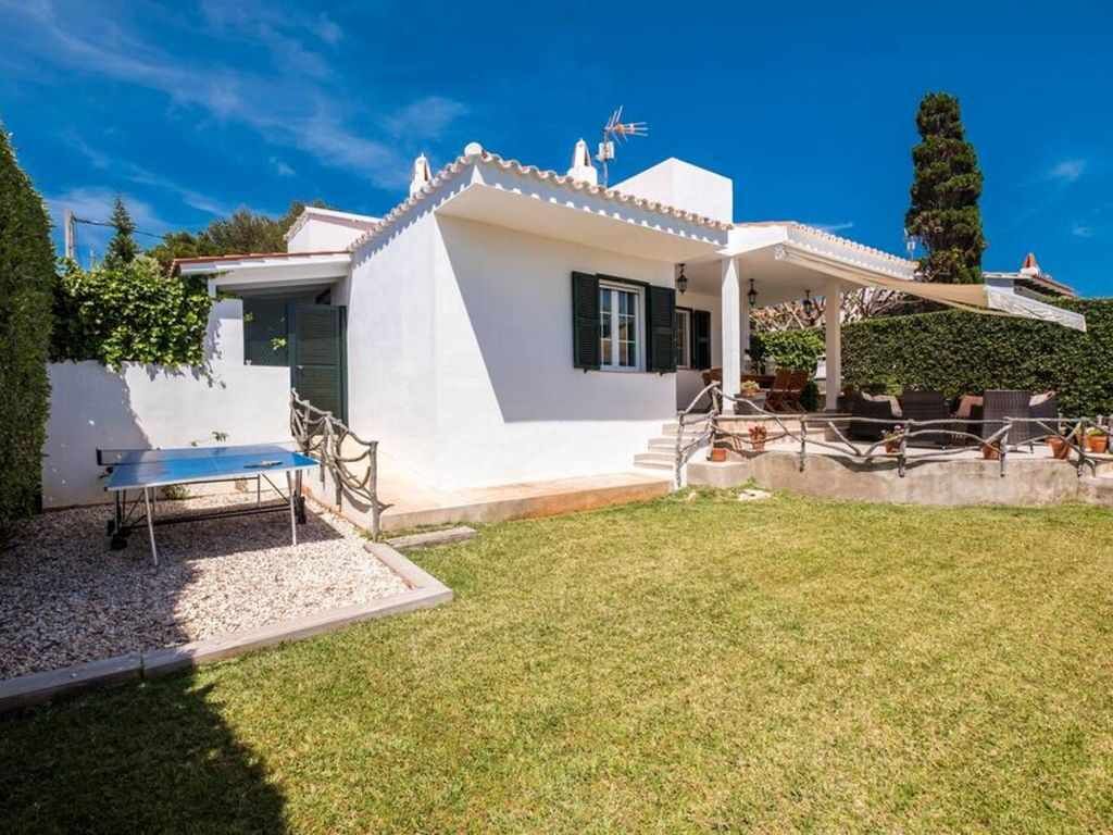 A white villa with a covered patio, a small garden, and a clear blue sky.