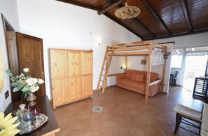 Une pièce rustique comprenant un lit superposé en bois, un canapé, une armoire et un coin repas.