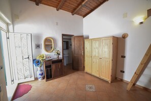 Une pièce avec un plafond en bois, un sol carrelé, une armoire en bois, un miroir et un vase rempli de fleurs.