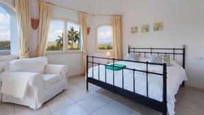A bedroom with a bed, a white sofa, and two windows with curtains.