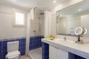 Une salle de bain équipée de toilettes, d’une douche, d’un lavabo et d’un miroir.